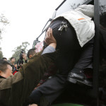 En man lyckas komma med en överfull buss till tågstationen från en temporär busshållplats, med hjälp... (AFP PHOTO/LIU Jin)