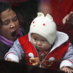 En kvinna gäspar med sin baby som tittar ut genom ett bussfönster, Guangzhou. (AFP PHOTO/LIU Jin)