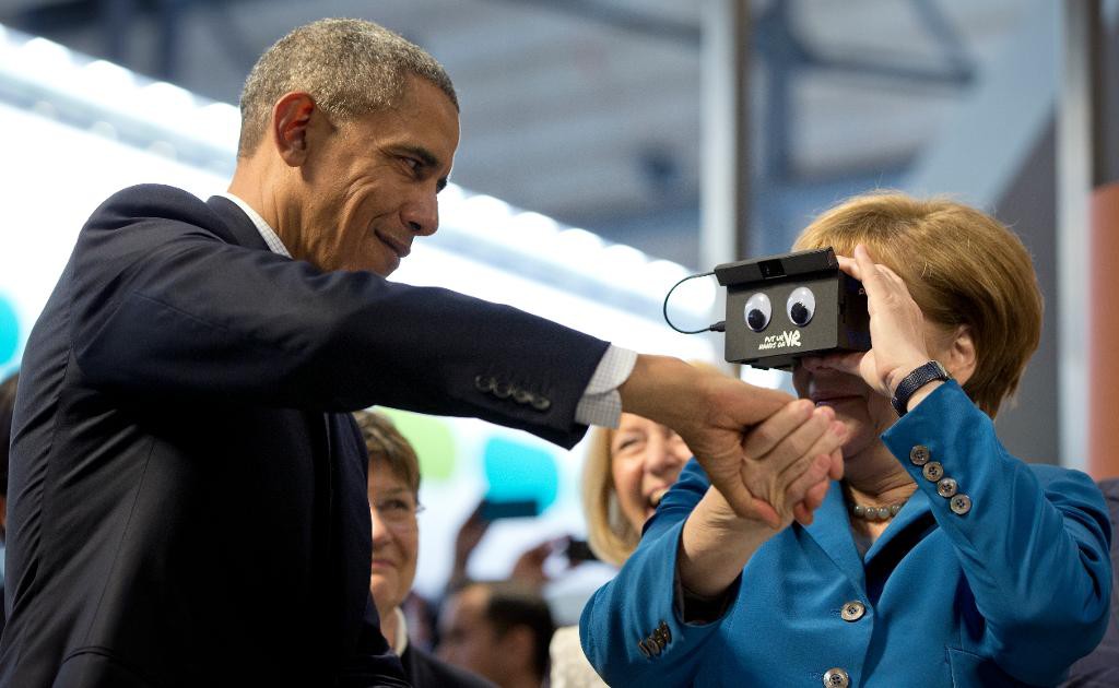 President Barack Obama håller förbundskansler Angela Merkel i handen när hon testar virtual reality-glasögon i på en industrimässa. Mötet i Hannover blir troligen Obamas sista besök i Tyskland under sin tid som president. (Foto: Carolyn Kaster /AP/TT)
