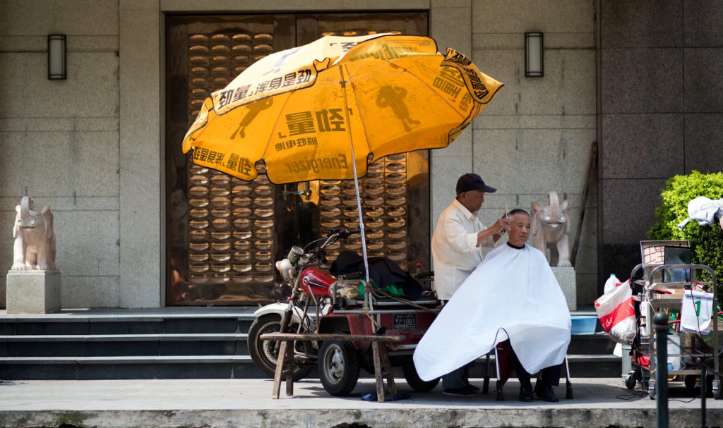 En frisör, en del av Kinas tjänstesektor, klipper håret på en kund i Shanghai. (Foto: Johannes Eisele/AFP/Getty Images)