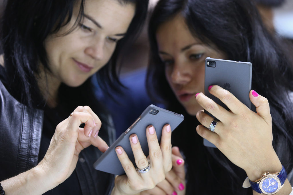 Två kvinnor testar Huawei-telefoner på en elektronikmässa i Berlin 2015. (Foto: Sean Gallup/Getty Images)