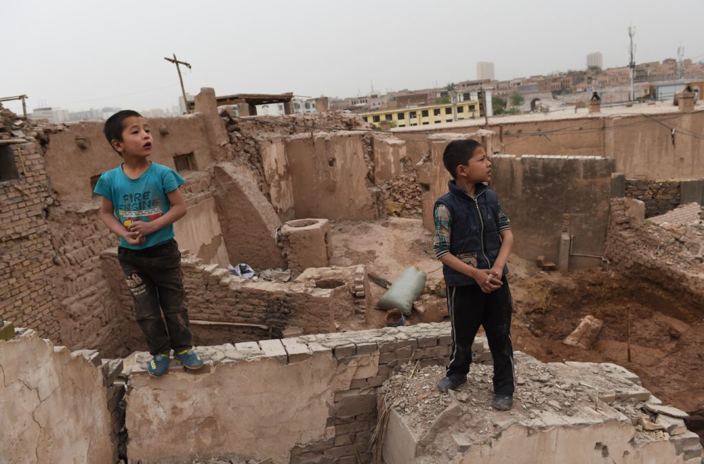 This photo taken on April 19, 2015 shows Uighur boys playing on the remains of houses in the old city in Kashgar, in China's western Xinjiang region. AFP PHOTO / Greg BAKER (Photo credit should read GREG BAKER/AFP/Getty Images)