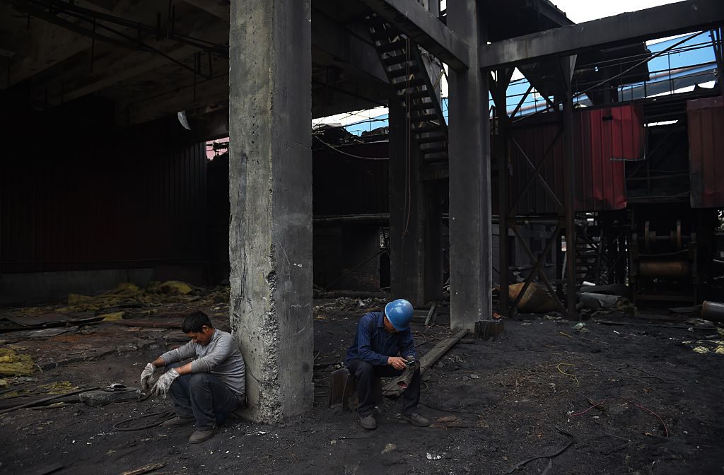 This photo taken on May 28, 2015 shows demolition workers resting after a day cleaning up an abandoned building at the Shougang Capital Iron and Steel plant in Beijing. Founded in 1919, Shougang was once the largest steel plant in China, with tens of thousands of workers. But the facility was identified as the Chinese capitals biggest polluter and began a gradual shutdown in 2005 as part of an effort to improve air quality ahead of the 2008 Olympics, finally producing its last steel in early 2011. Local officials have said the 8.6 square km (3.3 square mile) facility will be turned into an arts, tourism and finance hub, but progress has been slow and the decaying site is still reportedly blighted by soil pollution built up during the plants industrial heyday. AFP PHOTO / GREG BAKER (Photo credit should read GREG BAKER/AFP/Getty Images)
