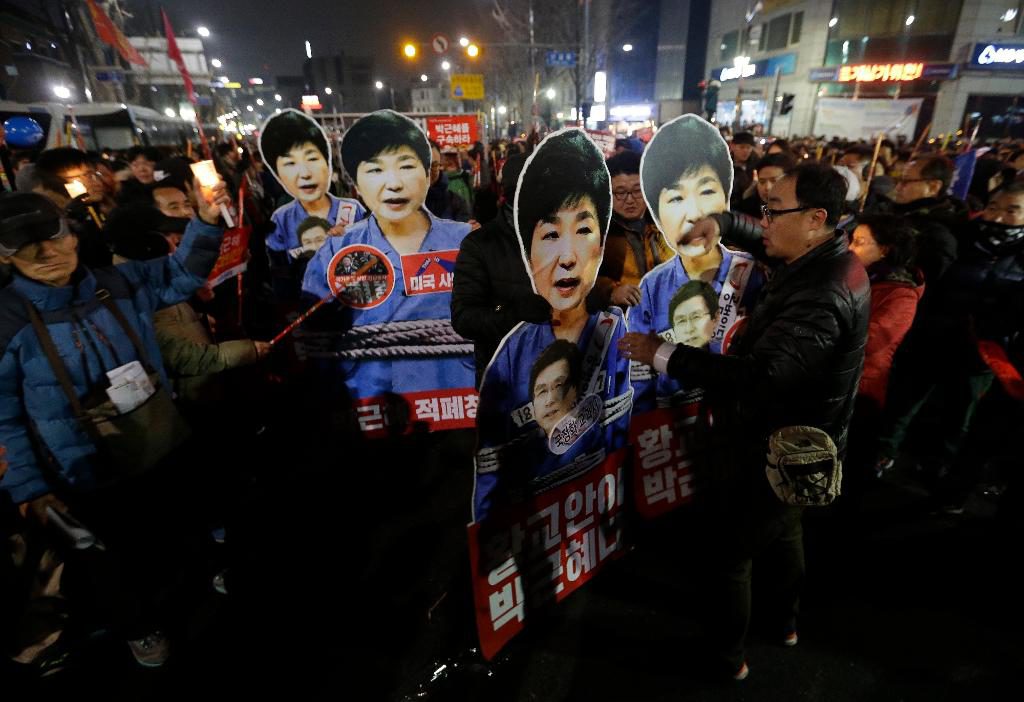 Demonstranter håller urklippta bilder på Sydkoreas president Park Geun-hye under en demonstration i Seoul på nyårsaftonen, där flera hundra tusen människor deltog. (Foto: Ahn Young joon/AP/TT)