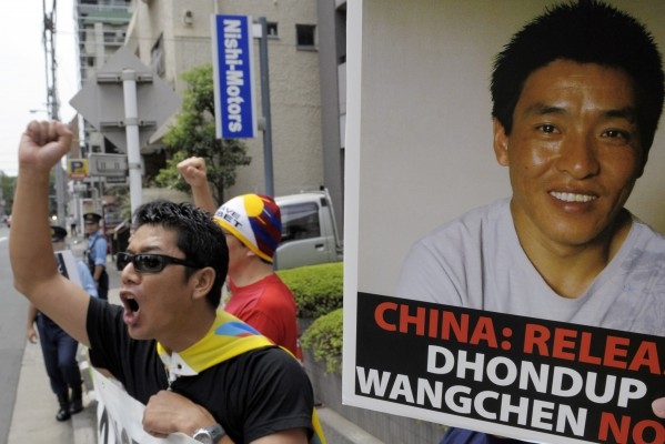 "Students for a Free Tibet Japan" ropar slagord under en demonstration där man kräver frigivning av den arresterade tibetanska regissören Dhondup Wangchen (affisch) framför den kinesiska ambassaden i Tokyo den 1 augusti 2009. Wangchen har varit fängslad i Kina sedan mars 2008 efter att i hemlighet gjort en dokumentärfilm. (Foto: AFP/Toshifumi Kitamura)
