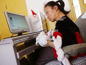 Wang Chunhui skriver dikter med hjälp av en ätpinne som hon håller mellan tänderna. (Foto: The Epoch Times)