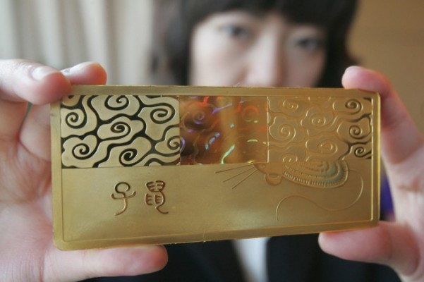 En anställd visar en guldtacka med en bild på en råtta, i Peking den 17 december 2007. (Foto: STR/AFP/Getty Images)