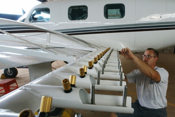 Flygteknikern Steve Bauer från det amerikanska företaget Weather Modification Inc. inspekterar sprutanordningen på ett plan som ska flyga in i molnen och skapa regn över Bangalore i Indien, vid en allvarlig torkperiod 2003. (Foto: AFP/Indranil Mukherjee)