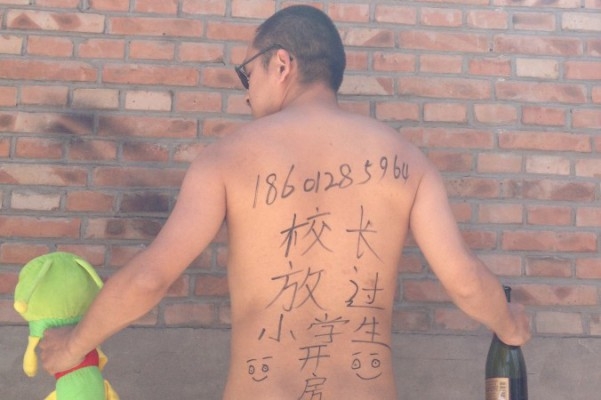 Poeten Wang Zang poserar på sin arbetsplats i Peking med de kinesiska tecknen ”Rektorn, skaffa ett rum [tillsammans med mig]. Låt de unga eleverna vara”, skrivna på ryggen samtidigt som han håller ett uppstoppat djur och en spritflaska. Konstnärer, aktivister, universitetsstudenter och poliser tar bilder av sig själva – en del nakna och provokativa, vissa arga och hotande – med samma budskap. (Foto: AP Photo/Courtesy of Wang Zang)
