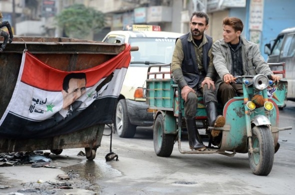 En flagga med ett porträtt av den syriske presidenten Bashar al-Assad på en sopcontainer i staden Aleppo i norra Syrien den 26 oktober. (Foto: Philippe Desmazes/AFP/Getty Images)