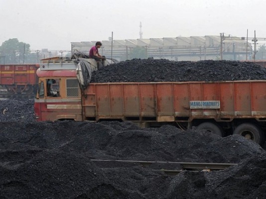 En indisk arbetare tar en paus efter att ha lastat upp kol på lastbilar i Kankarias bangård i Ahmedabad i september. Indien har planerat att bygga 455 kolkraftverk för att uppfylla sin skyhöga efterfrågan på energi. (Foto: Sam Panthaky / AFP / GettyImages)
