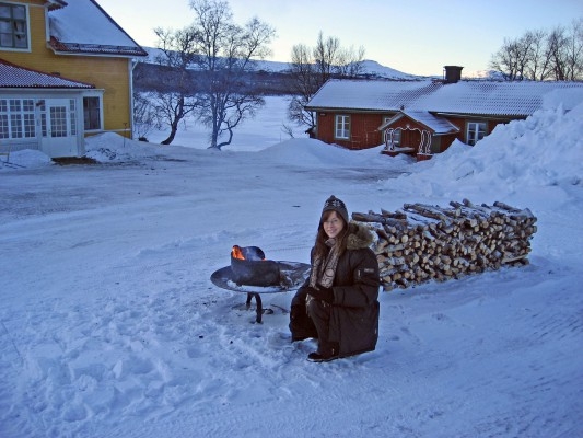 Turist som värmer sig  vid elden  en kylig  januaridag  vid  den nyrenoverade hotellanläggningen Fjällnäs Est.1882 (Foto: Susanne Larsson, Epoch Times)