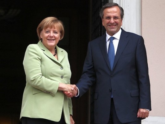 Greklands premiärminister Antonis Samaras och Tysklands förbundskansler Angela Merkel skakar hand i Aten den 9 oktober. (Foto: Thanassis Stavrakis /AFP /Getty Images)
