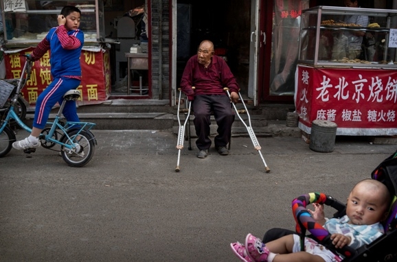 En gammal man sitter utanför sitt hus i Peking. (Foto: Kevin Frayer/Getty Images)