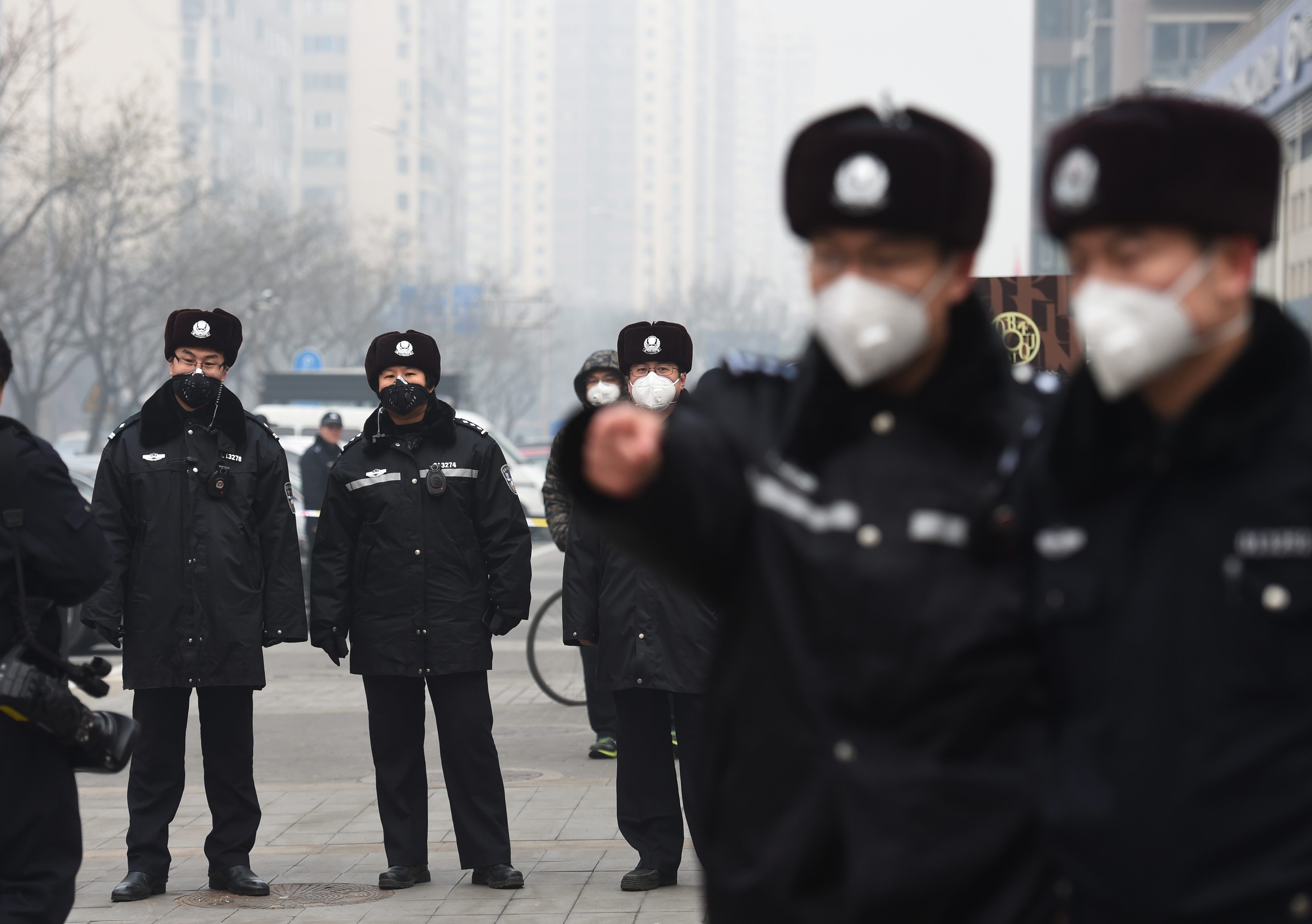 Poliser med munskydd vaktar utanför rättegången mot människorättsadvokaten Pu Zhiqiang, Peking den 22 december 2015.  Pu dömdes till tre års fängelse för skriftlig kritik mot kommunistregimen. Han är en av dem som råkat ut för Kinas nedslag mot människorättsadvokater och icke-statliga organisationer det senaste halvåret. Den 4 januari häktades svensken Peter Dahlin som jobbade för rättssäkerhet i Kina genom en människorättsorganisation.  (Foto: Greg Baker/AFP/Getty Images)