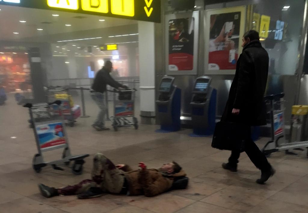 
En skadad man ligger på golvet i den rökfyllda flygplatsen efter attentatet, som uppges ha kostat minst 14 människoliv. (Foto: Ketevan Kardava /AP/TT)