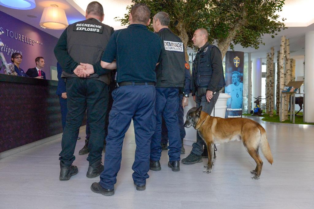 Säkerhetspersonal, med bombhund, rör sig på hotellet. (Foto: Janerik Henriksson/TT)