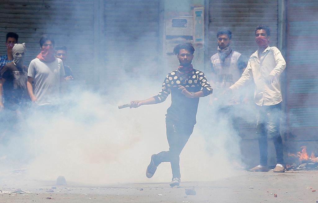 En demonstrant kastar tillbaka en tårgasbehållare mot regeringstrogna militärer i Srinagar, Kashmir, efter mordet på en populär rebelledare. (Foto: Mukhtar Khan/AP/TT-arkivbild)