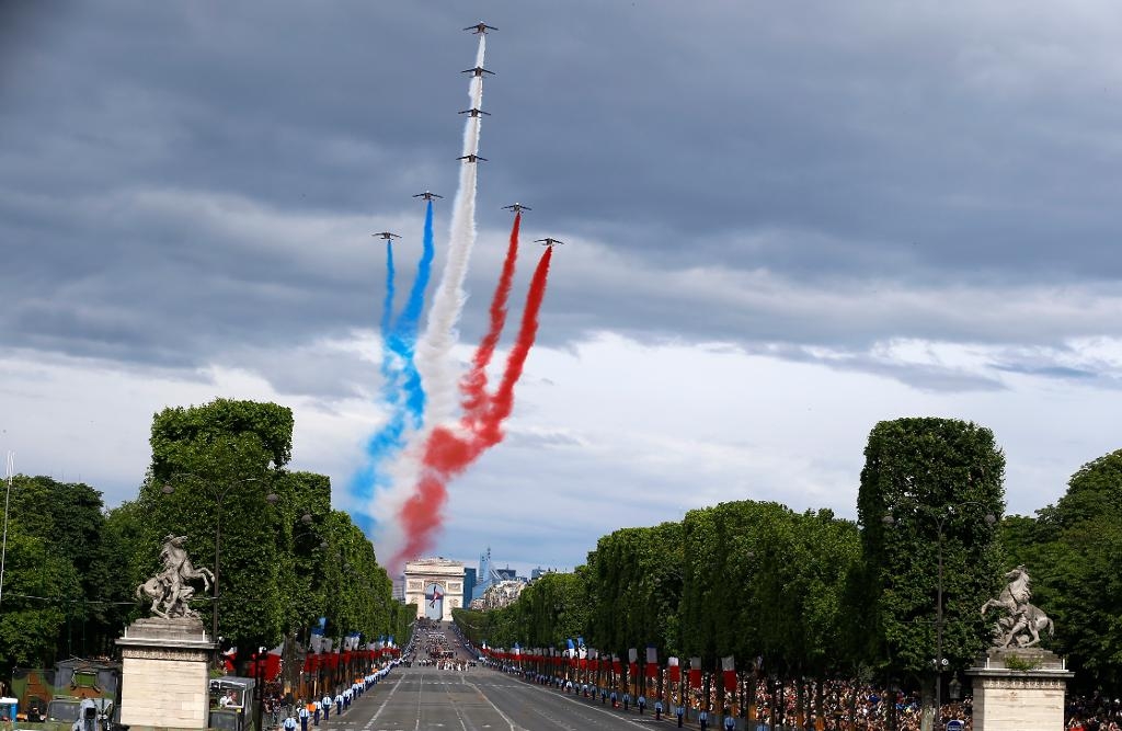 Plan från det franska flygvapnets uppvisningsgrupp flyger över paradgatan Avenue des Champs-Elyssés. (Foto: Francois Mori/AP/TT)