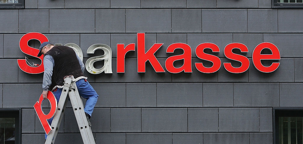 En arbetare reparerar Sparkassebankens skylt i Berlin. Tyskarna sparar i större grad kontanter i sina egna hem.  (Foto: Sean Gallup/Getty Images)