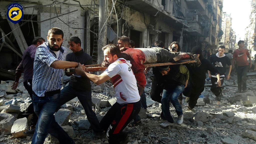 Hjälparbetare från organisationen Vita hjälmarna bär ett offer för en bombräd i östra Aleppo under tisdagen. (Foto: Vita hjälmarna/AP/TT)