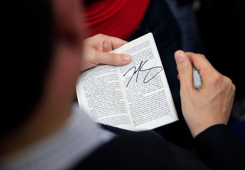 Valreglerna togs fram samtidigt som USA:s konstitution på 1700-talet. Här skriver politikern Ted Cruz på ett exemplar av grundlagen under valrörelsen tidigare i år. (Foto: John Locher/AP/TT)