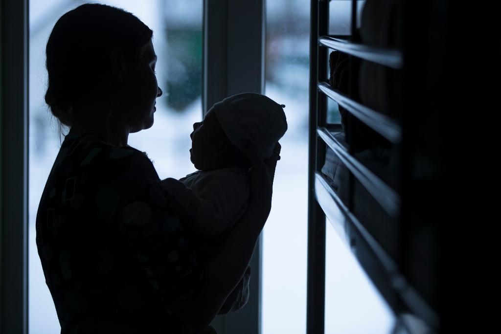 En kvinna som misshandlats av sin make håller sitt barn på ett härbärge för kvinnor som utsatts för våld i hemmet i Ryssland.  Foto: Pavel Golovkin /AP/TT
