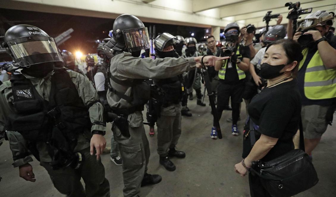 
Kravallpolis säger åt en kvinna att ta av sin ansiktsmask under protesterna i söndags. Foto: Dita Alangkara/AP/TT                                                