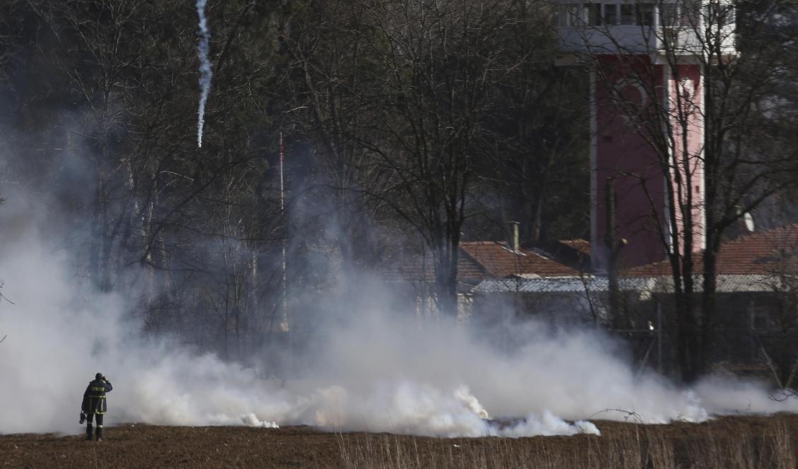 En grekisk brandman nära gränsstängslet medan tårgas används under sammandrabbningar vid gränsen mellan Grekland och Turkiet. Foto: Giannis Papanikos/AP/TT