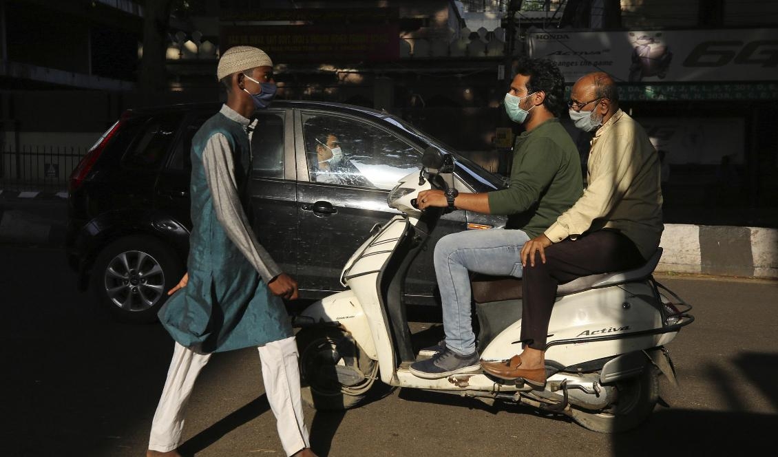Indier med munskydd under nedstängning i Bangalore under fredagen. Foto: Aijaz Rahi/AP/TT