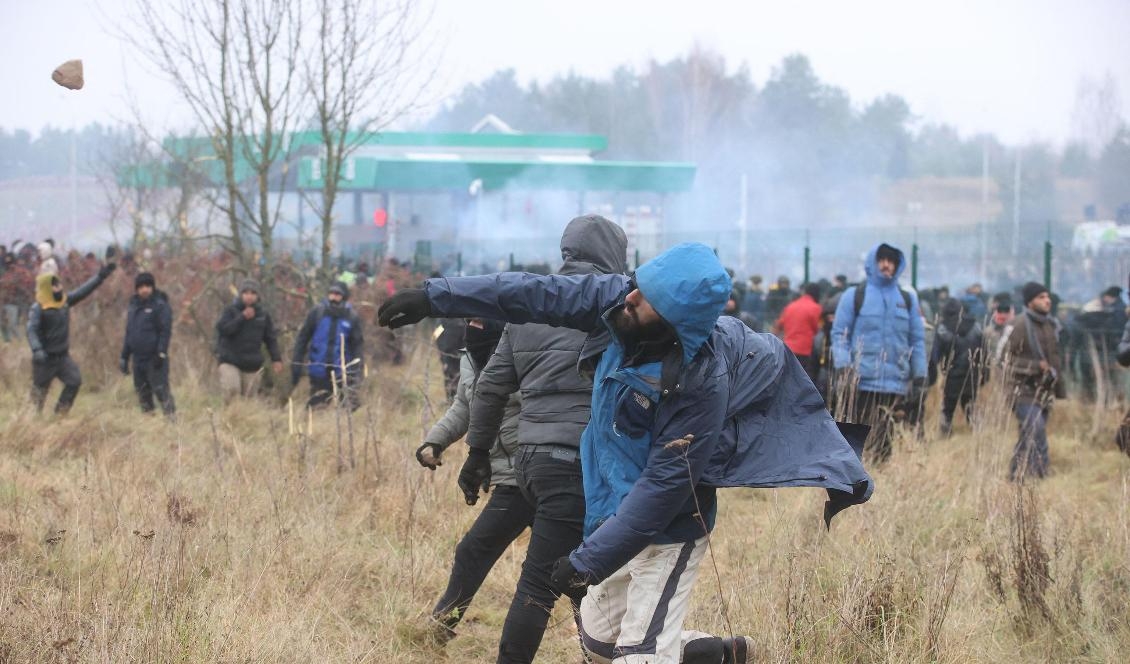 
Migranter kastar sten mot polska soldater i Bruzgi-Kuznica vid gränsen mellan Belarus och Polen den 16 november 2021. Foto: Leonid Shcheglov/Belta/AFP via Getty Images                                            