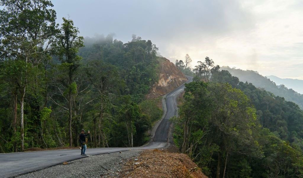 En man tar selfies på en uppgraderad väg i Indonesiens Aceh-provins den 12 mars. Nu går här en modern väg med asfalt. Unesco har protesterat för det här är en skyddad skog sedan 1984, men alltmer av mänskliga aktiviteter tränger sig in. Foto: Chaideer Mahyuddin/AFP via Getty Images