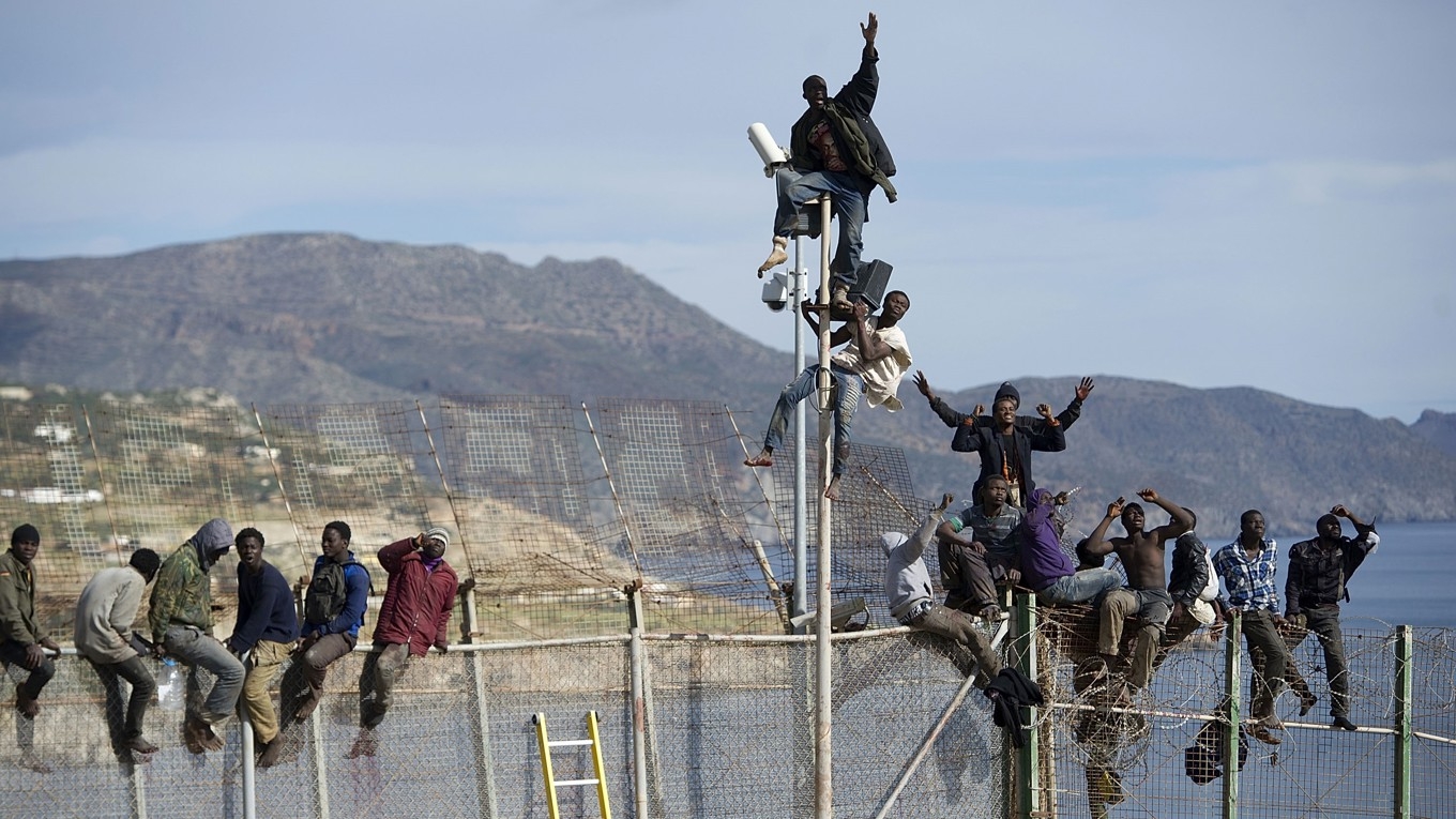 Afrikanska migranter försöker ta sig över stängslet vid gränsen mellan Marocko och den nordafrikanska spanska enklaven Melilla den 3 april 2014. Foto: Alexander Koerner/Getty Images