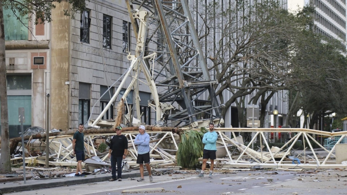 Invånare undersöker förödelsen sedan en lyftkran fallit över ett hus i Tampa till följd av Miltons orkanvindar. Foto: Tampa Bay Times via AP/TT