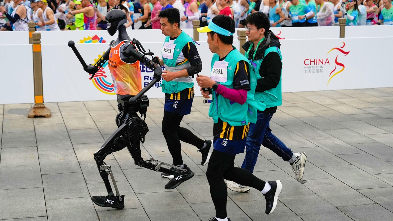 Några robotar föll redan vid starten, andra kraschade mot räcken eller behövde fångas upp av operatörer som sprang bredvid, beredda att ingripa. Foto: Ng Han Guan/AP/TT