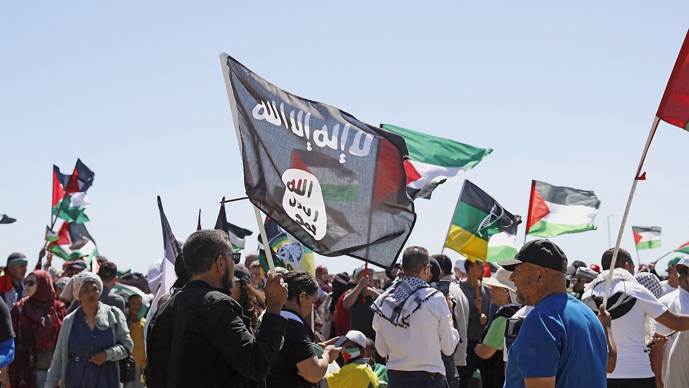 En man håller i en IS-flagga vid en pro-palestinsk demonstration i Sydafrika. Islamiska staten betecknar anhängare av andra religioner och andra riktningar inom islam som otrogna. Foto: Gianluigi Guercia/AFP via Getty Images