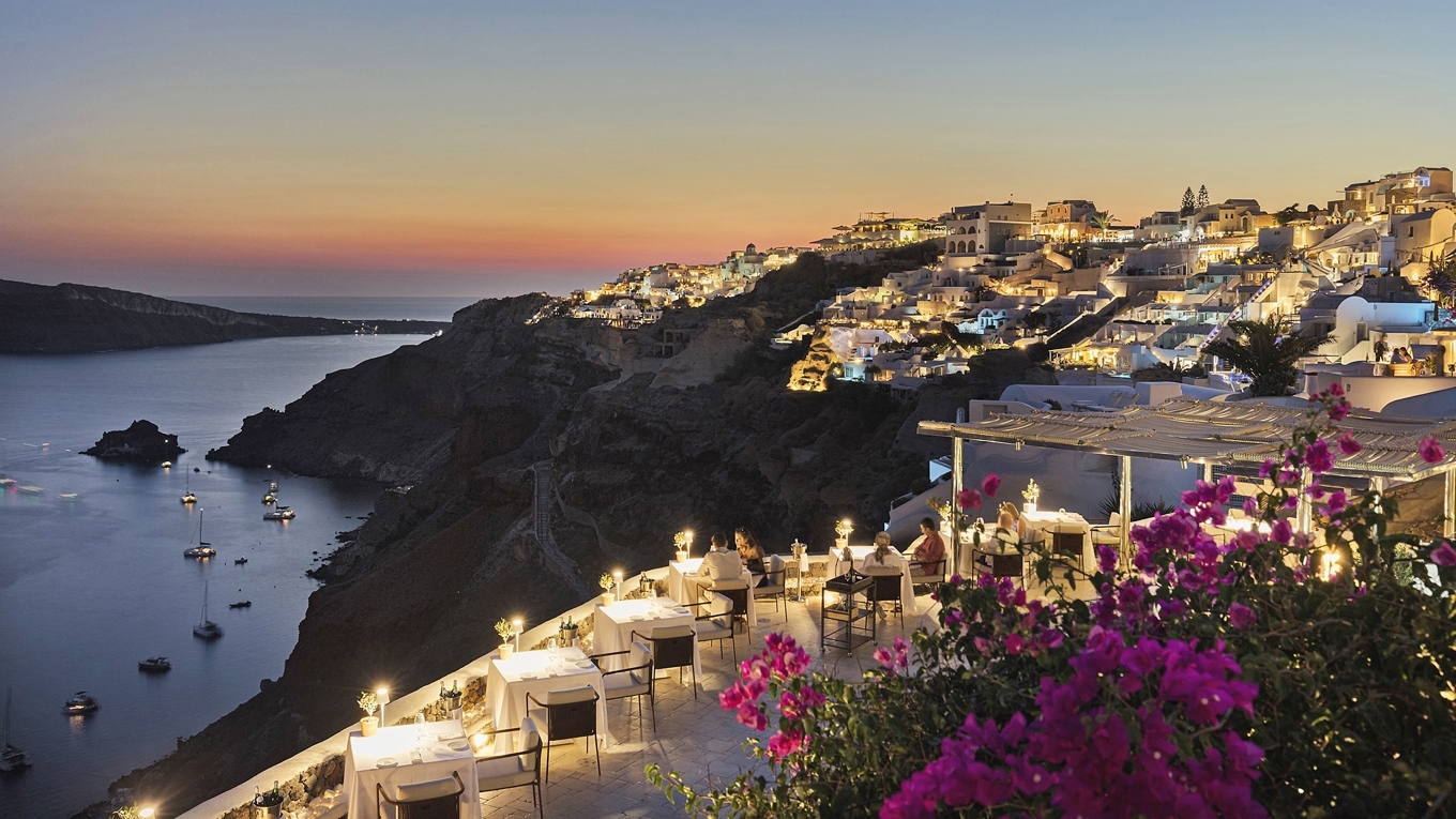 Hotellet Canaves Oia Suites ligger dramatiskt uthugget i de vita kalkstensklipporna ovanför den vulkaniska krater som ger Santorini sin unika geografi. Foto: Canaves Oia Suites