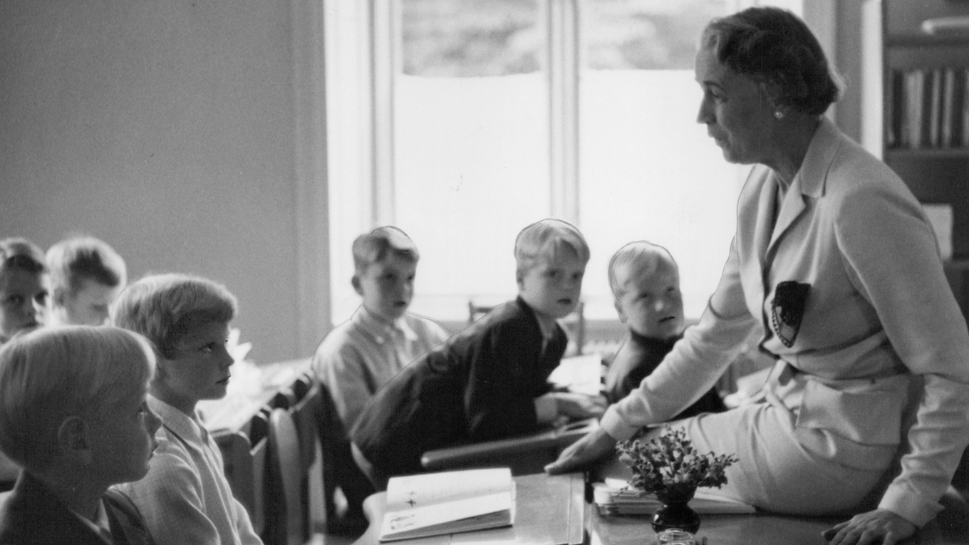 Skolans ägare Anna Broms har den 7 september 1954 samlat kronprins Carl Gustaf (tvåa från vänster) och hela klassen till första lektionen, andra skolåret i Broms skola. Fru Broms höll skolan i ett fast och personligt grepp, med en, som många uppfattade det, gammaldags disciplin.   
Foto: Svd/TT BILD