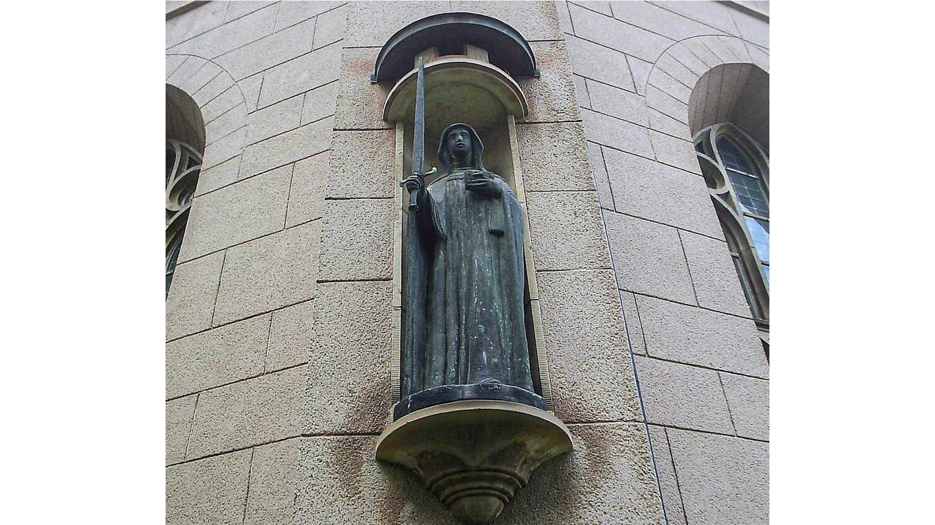 1950 skapade Astri Taube en gestaltning i brons av Elin av Skövde.
Den pryder nu Sankta Helena kyrka i Skövde. Helgonet bär sina attribut änkedoket, boken och svärdet. Foto: Harri Blomberg