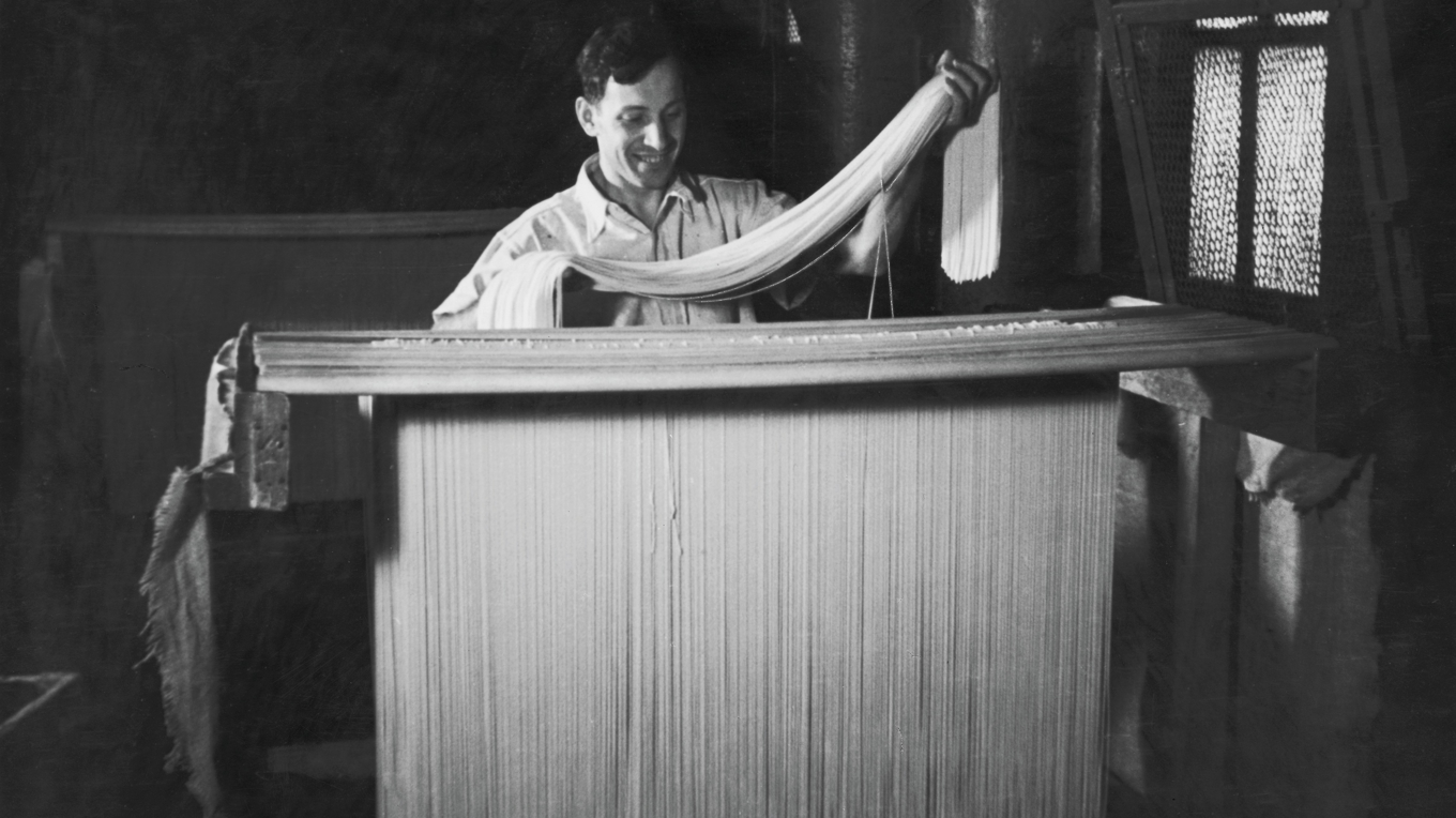 En arbetare i Italien på 1950-talet hänger upp nygjord spagetti på torkstänger. Den finaste pastan som tillverkades i Gragnano i Neapel torkades förr långsamt utomhus i det fuktiga klimatet. Foto: Hulton Archive/Getty Images