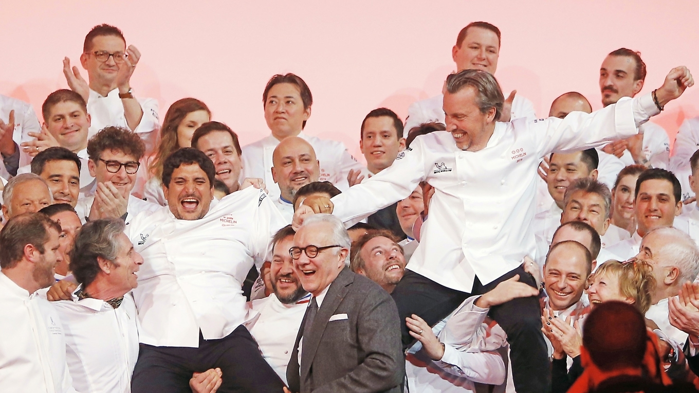Laurent Petit (till höger) från krogen Clos des Sens i franska Alperna och Mauro Colagreco (till vänster) från Mirazur på franska rivieran firar tre Michelinstjärnor på scenen under 2019 års guideceremoni i Paris. Alain Ducasse står i mitten. Foto: Rafael Yaghobzadeh/AP/TT