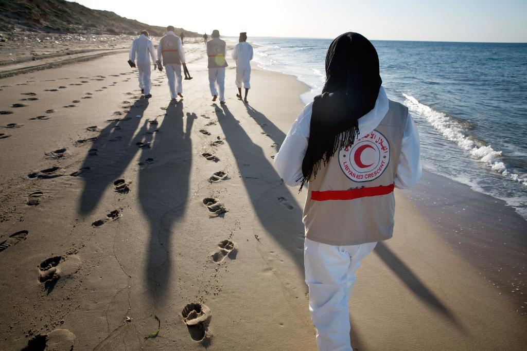 Hjälparbetare samlar ihop kroppar från drunknande migranter på stränderna utanför libyska Tripoli. (Foto: Mohame Ben Khalifa /AP/TT)