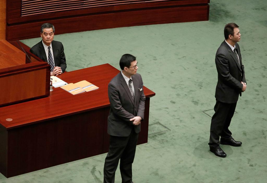 Säkerhetsvakter står framför Leung Chun-Ying under en paus i Hongkong-ledarens avskedstal. (Foto: Vincent Yu/AP/TT)