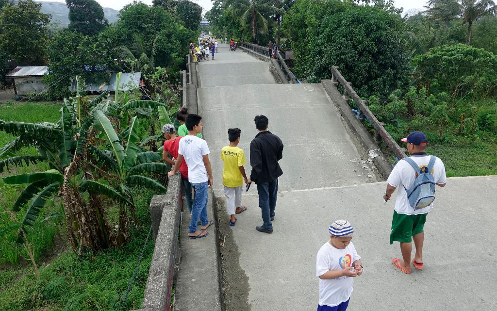 Invånare tittar på en förstörd bro i Surigao. Foto: AP/TT