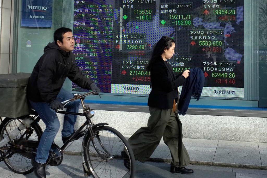 
Människor passerar utanför en börsskylt i Tokyo.  Foto: Shuji Kajiyama/AP/TT-arkivbild                                            