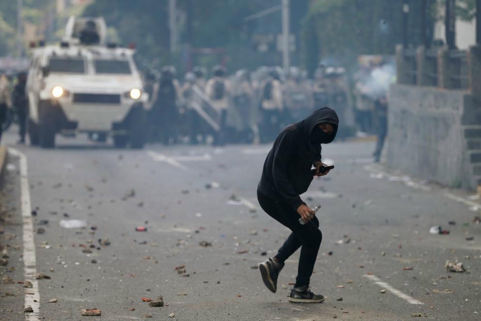 
En demonstrant kastar en flaska mot polisen i Caracas. Foto: Fernando Llano/AP/TT                                            