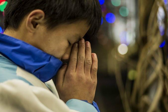 

En kristen kines ber under julmässan i en katolsk kyrka i Peking 2014. Foto: Fred Dufour/AFP/Getty Images                                                                                        