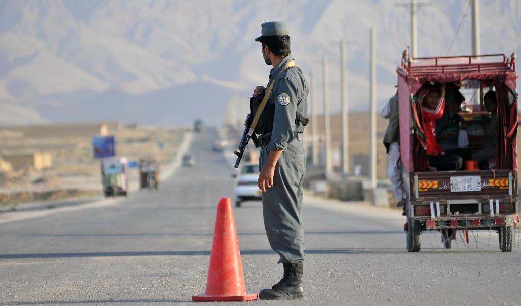 En afghansk polis står posterad i Mazar-i Sharif, där ett okänt antal amerikanska soldater på lördagen skadades i en misstänkt insiderattack. Arkivbild. Foto: Mustafa Najafizada AP/TT