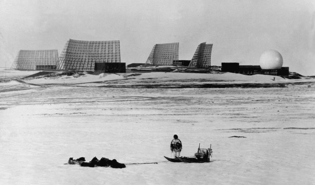 
En grönländare med hund framför USA:s Thule Air Base på norra Grönland 1966. Flygbasen var ingen hemlighet - det var däremot Camp Century, som när denna bild togs fortfarande sjöd av aktivitet under isen 24 mil bort. Foto: AFP/Scanpix/NF                                            