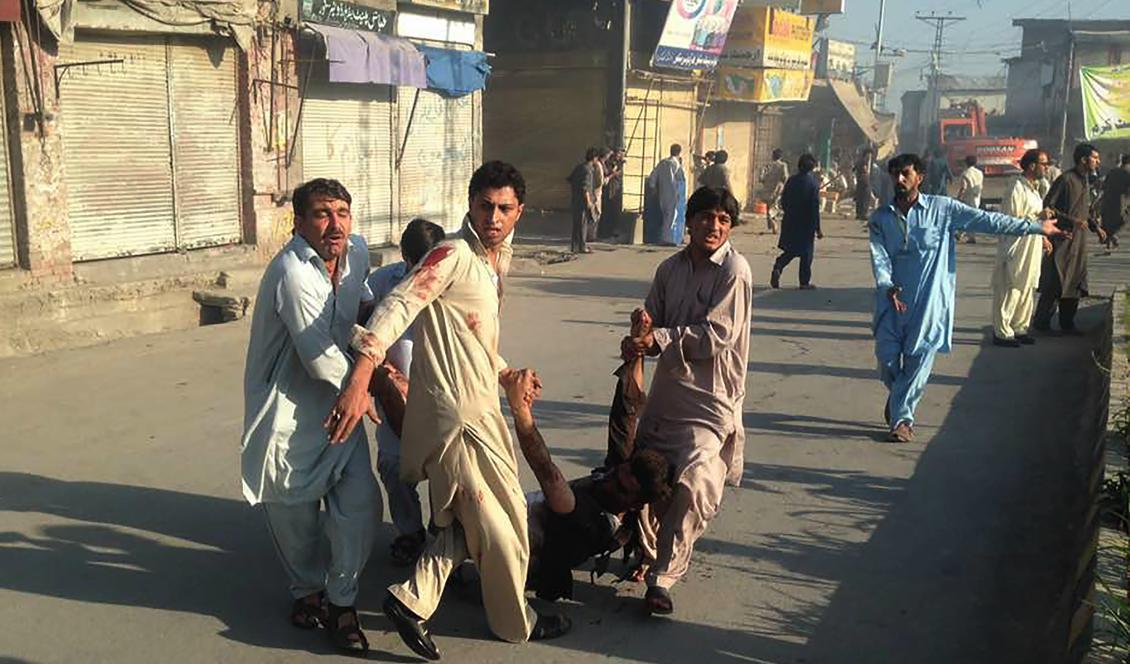 De boende försöker bära bort en skadad person. Två bomber exploderade på marknaden i Parachinar, Pakistan. Foto: STR/AFP/Getty Images